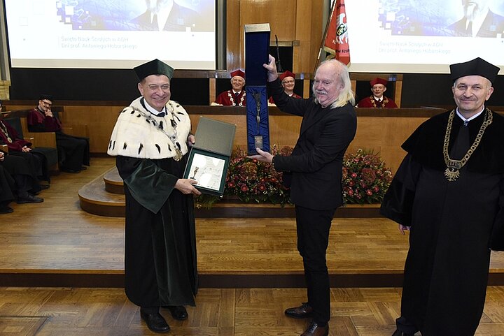 Zdjęcie przedstawia głównie trzech mężczyzn. Dwóch trzyma nagrodę i dyplom.