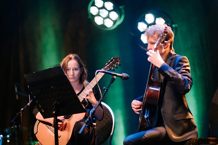 Zdjęcie przedstawia dwie osoby grające na gitarach.