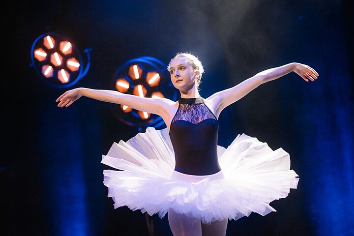Zdjęcie przedstawia baletnicę podczas występu na scenie.