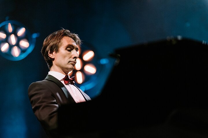 Zdjęcie przedstawia pianistę podczas występu na scenie.